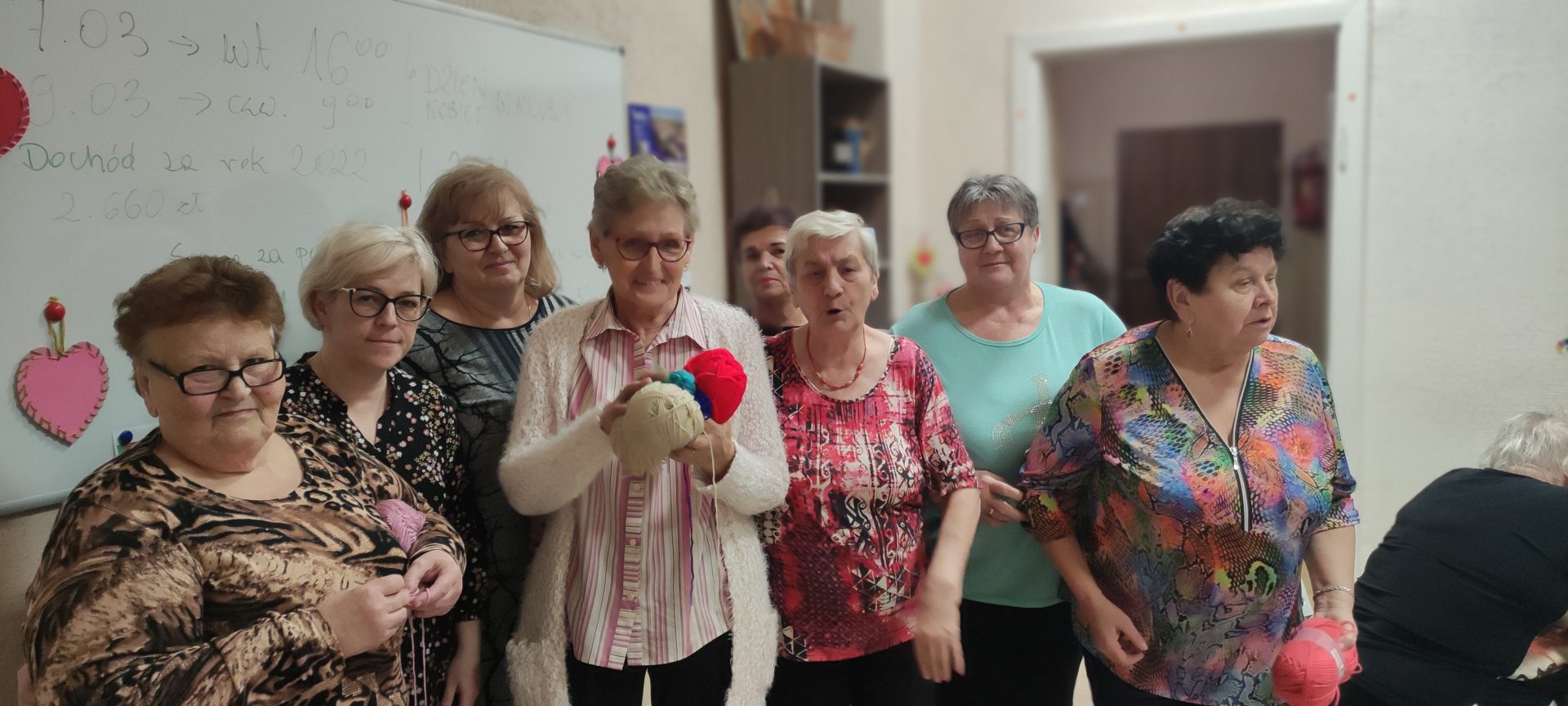 Fotografia przedstawia osiem kobiet z grupy Pikotek. Dwie trzymają kolorowe włóczki.