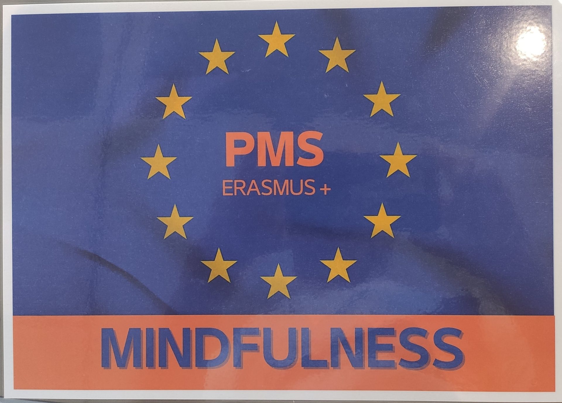 Logo organizatora szkolenia. Napis MINDFULNESS u dołu. Na niebieskim tle flaga Unii Europejskiej a w środku napis PMS Erasmus+.