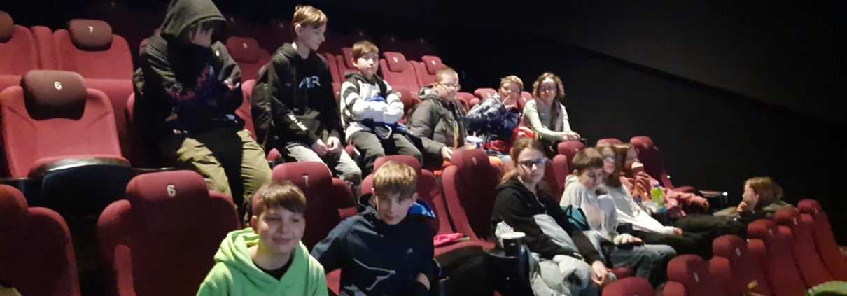 Uczniowie siedzący na sali kinowej.